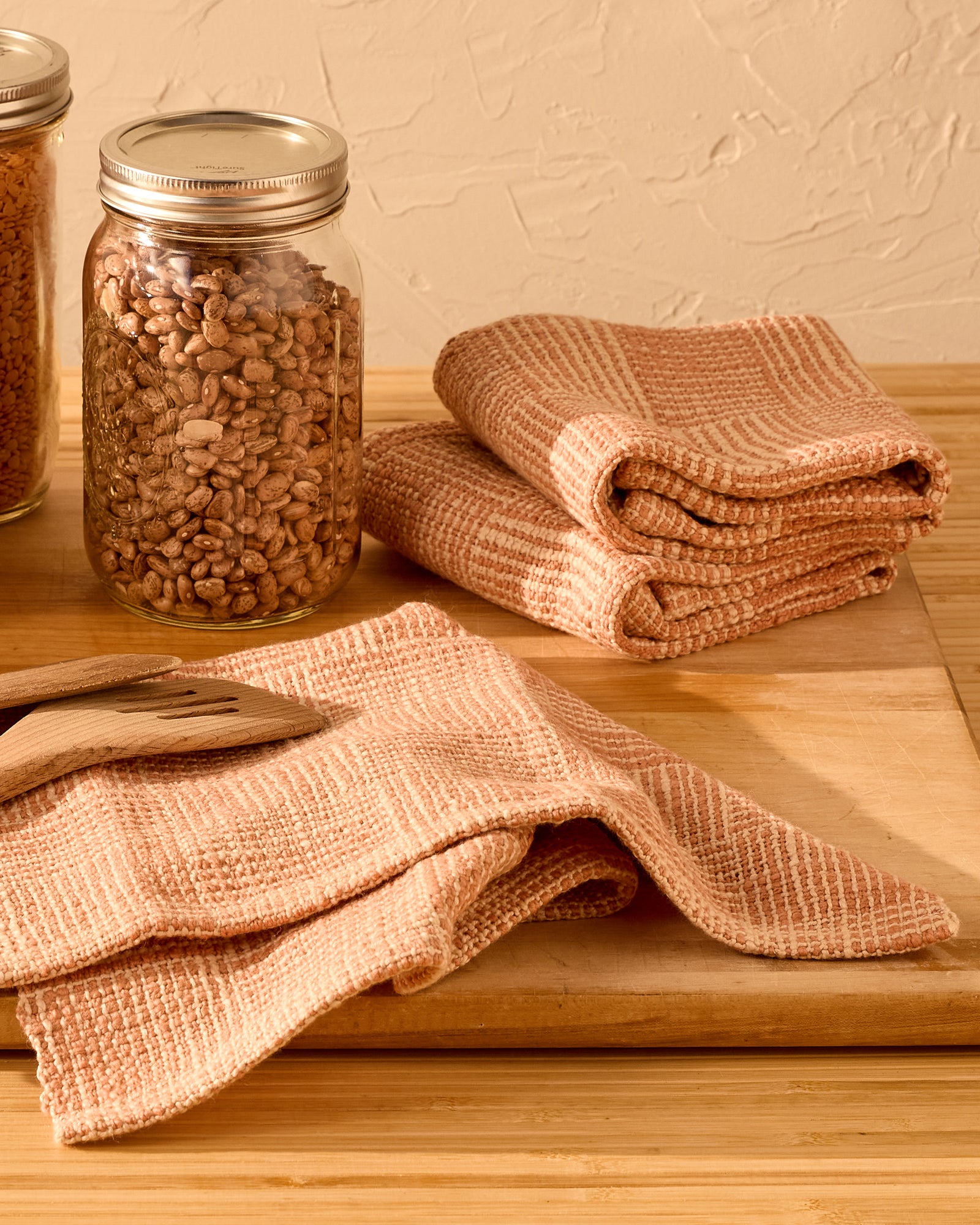 adobe towels on a wooden cutting board, with beans in a jar