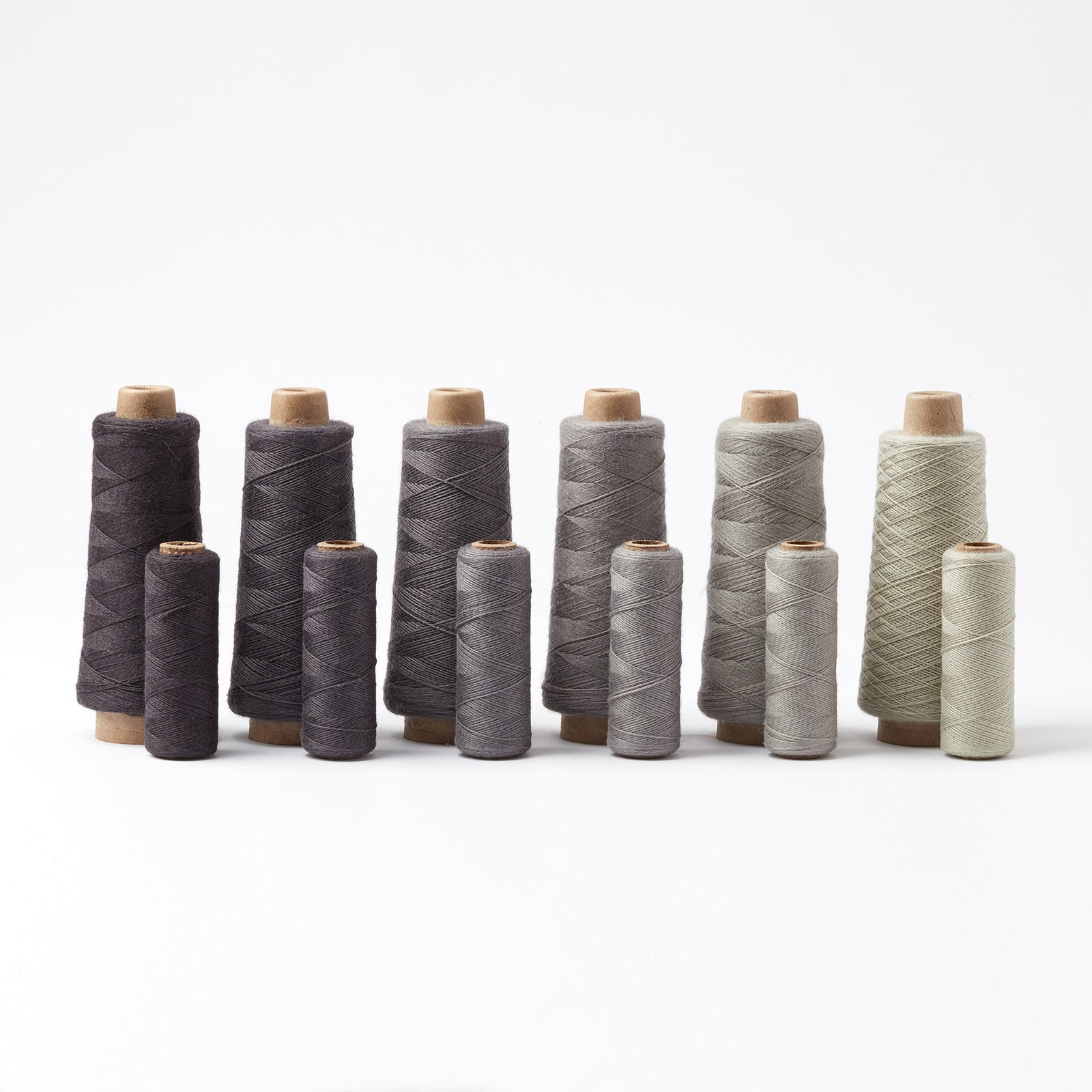 Array Wool Yarn ~ Black in various grey and black shades on cones and tubes, perfect for home decor and textiles.