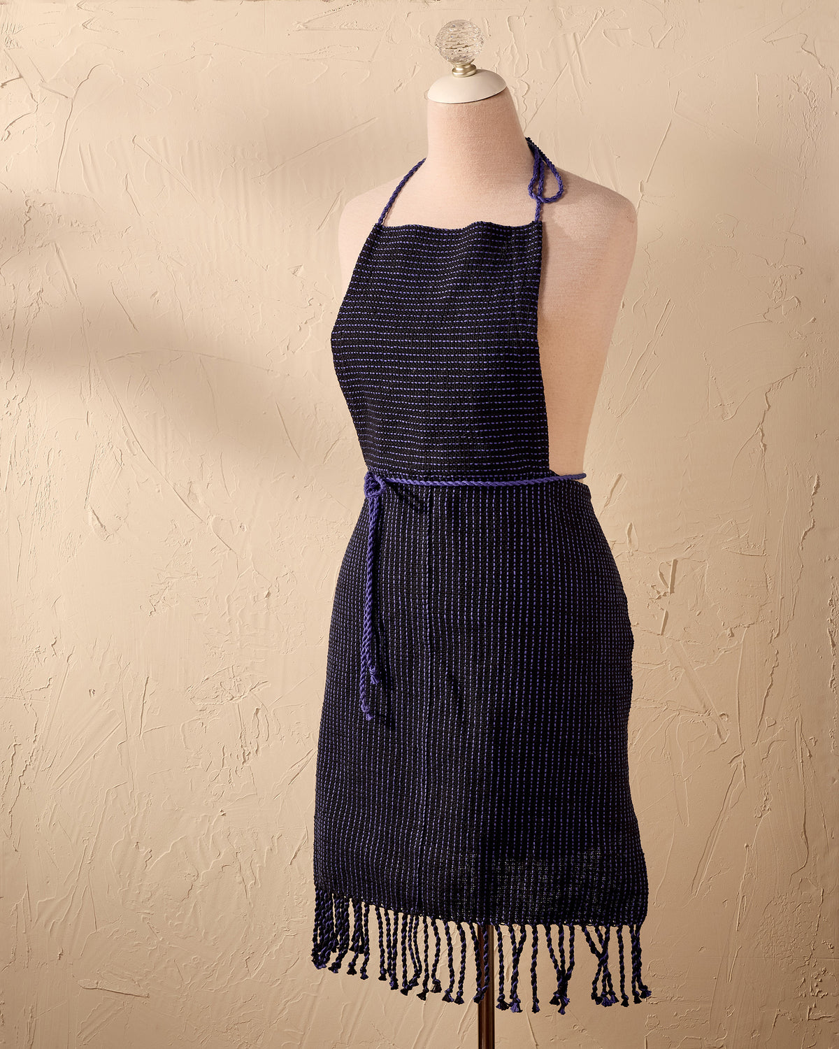 blue handwoven apron on a mannequin against a beige background