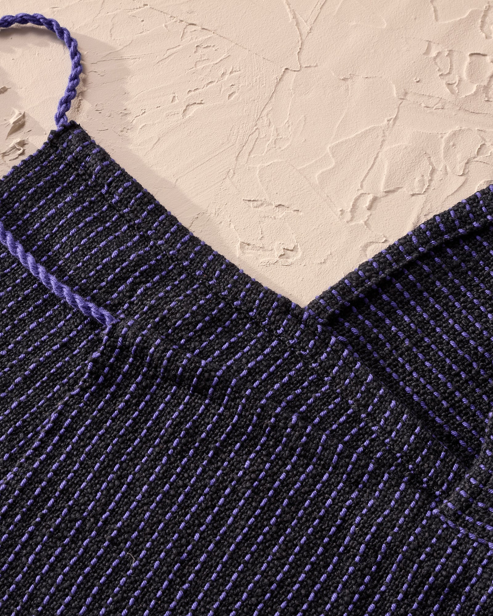 Close-up of a blue woven apron with a beige background