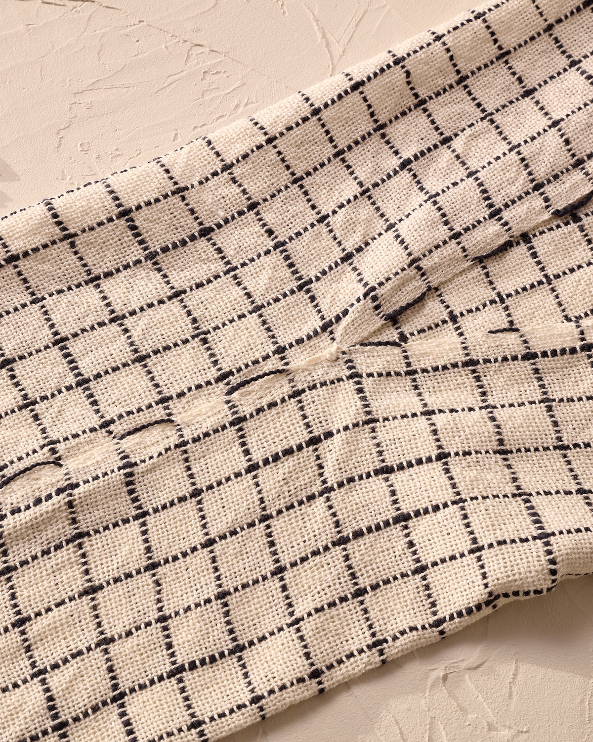 Close-up of a textured fabric with a grid pattern on a neutral background