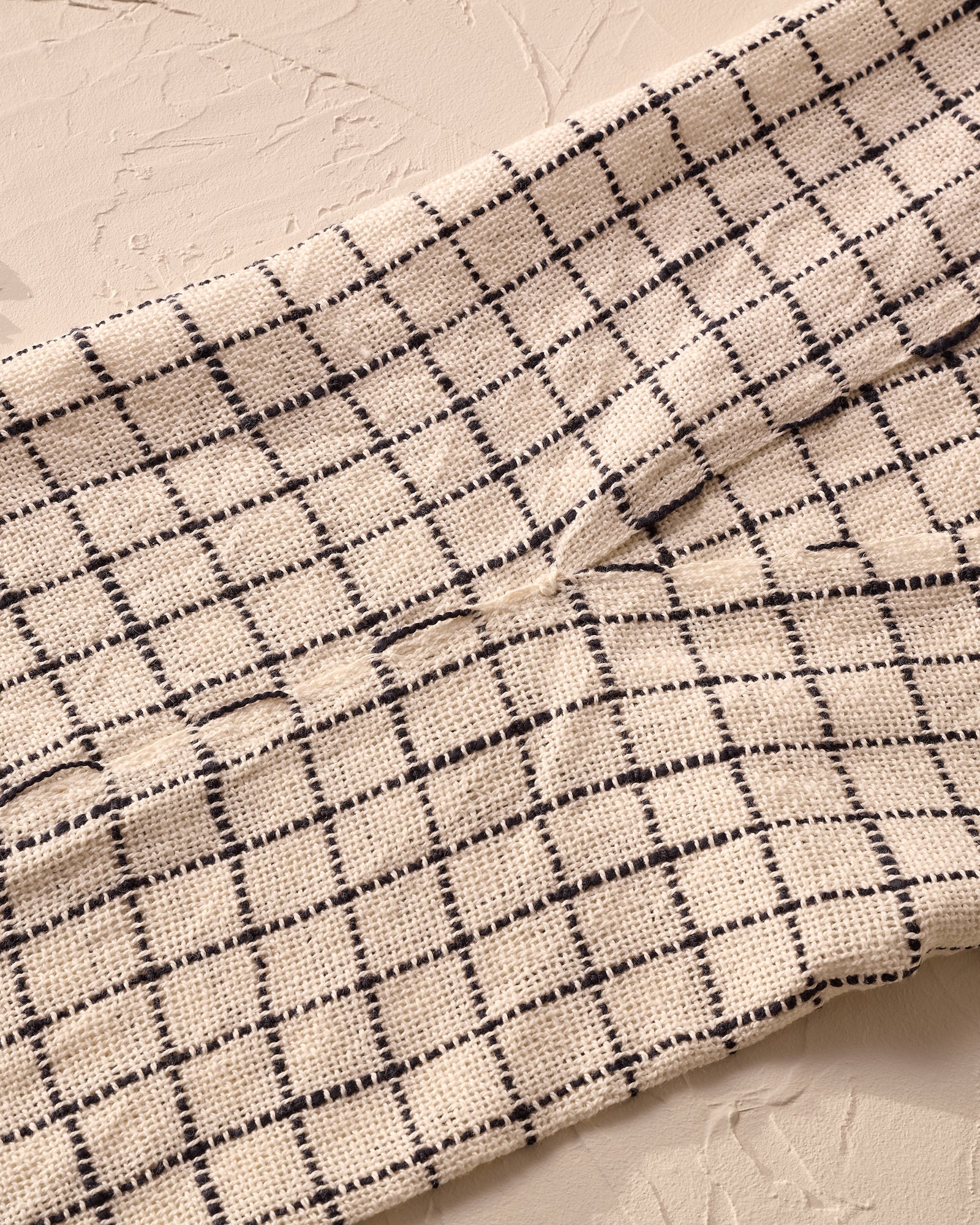 Close-up of a textured fabric with a grid pattern on a neutral background