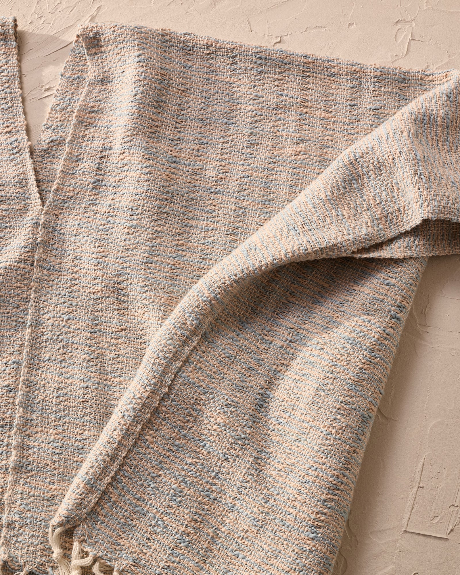 Textured handwoven fabric with a neutral color palette on a beige background