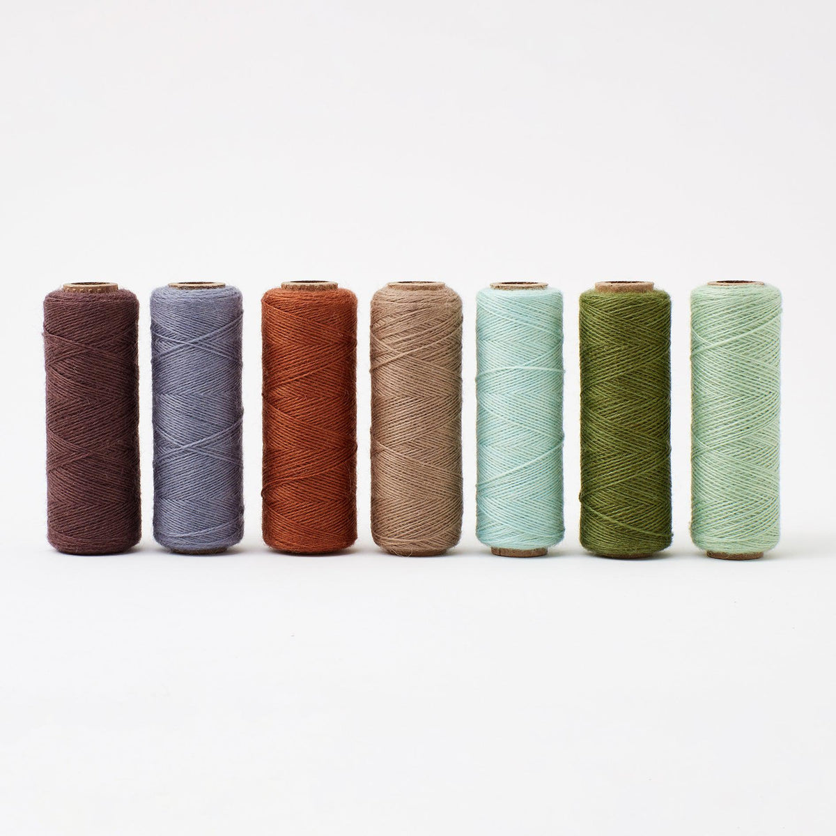 Array Nature Sampler Pack showing seven colorful wool yarn tubes in natural tones on a white background