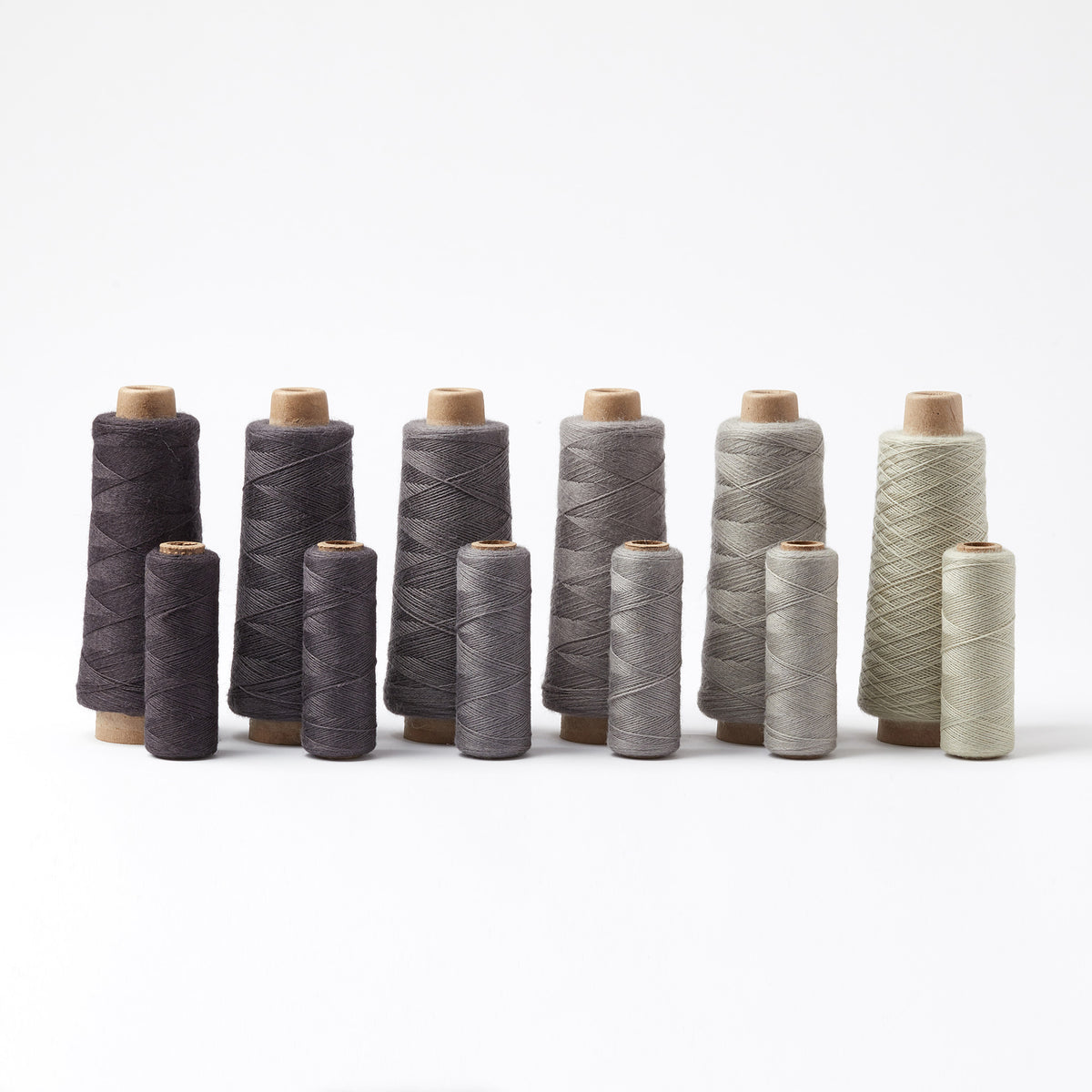Array Wool Yarn ~ Black in various grey and black shades on cones and tubes, perfect for home decor and textiles.