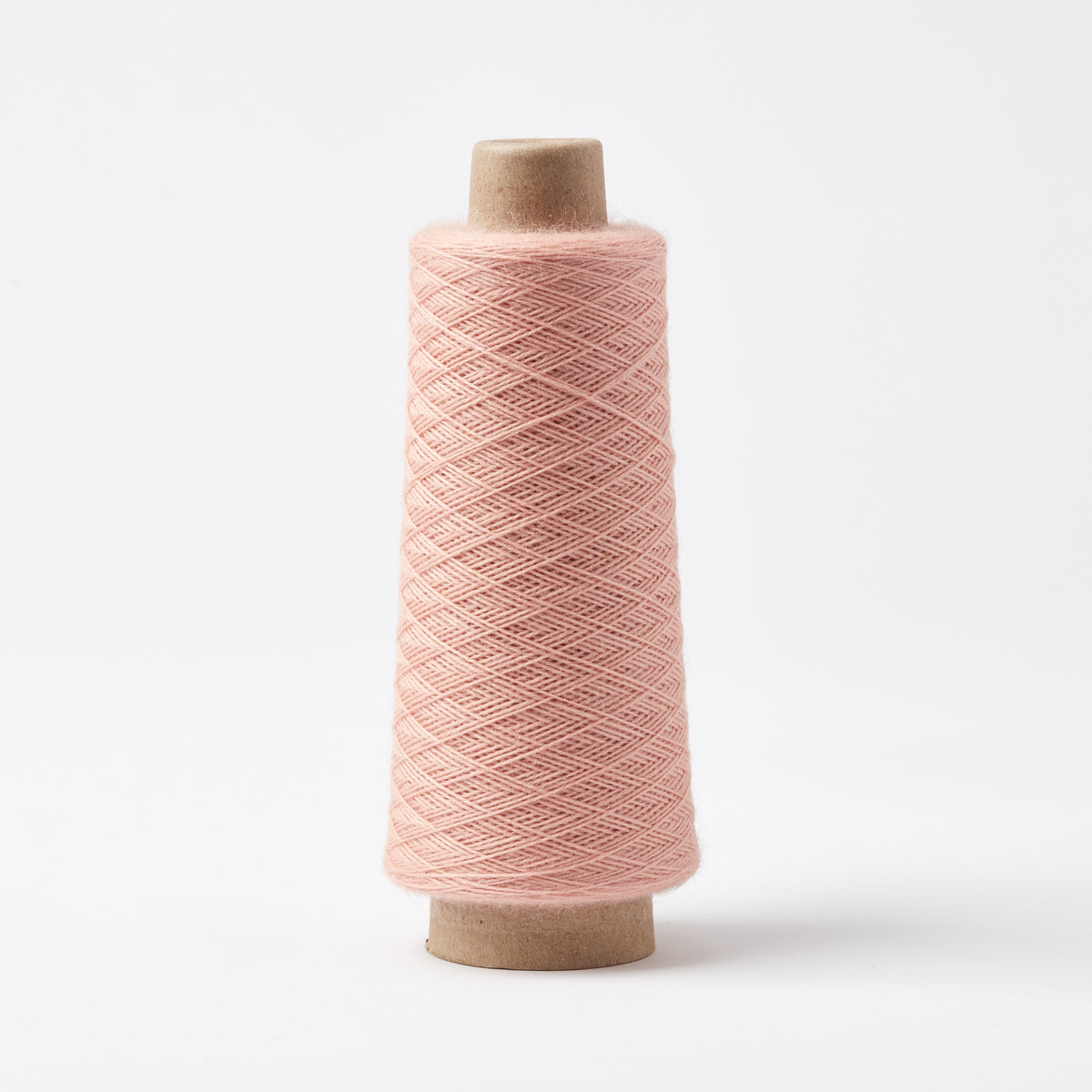 Array Wool Yarn ~ Cayenne cone showing thin, sturdy worsted spun yarn in soft pink color on white background.