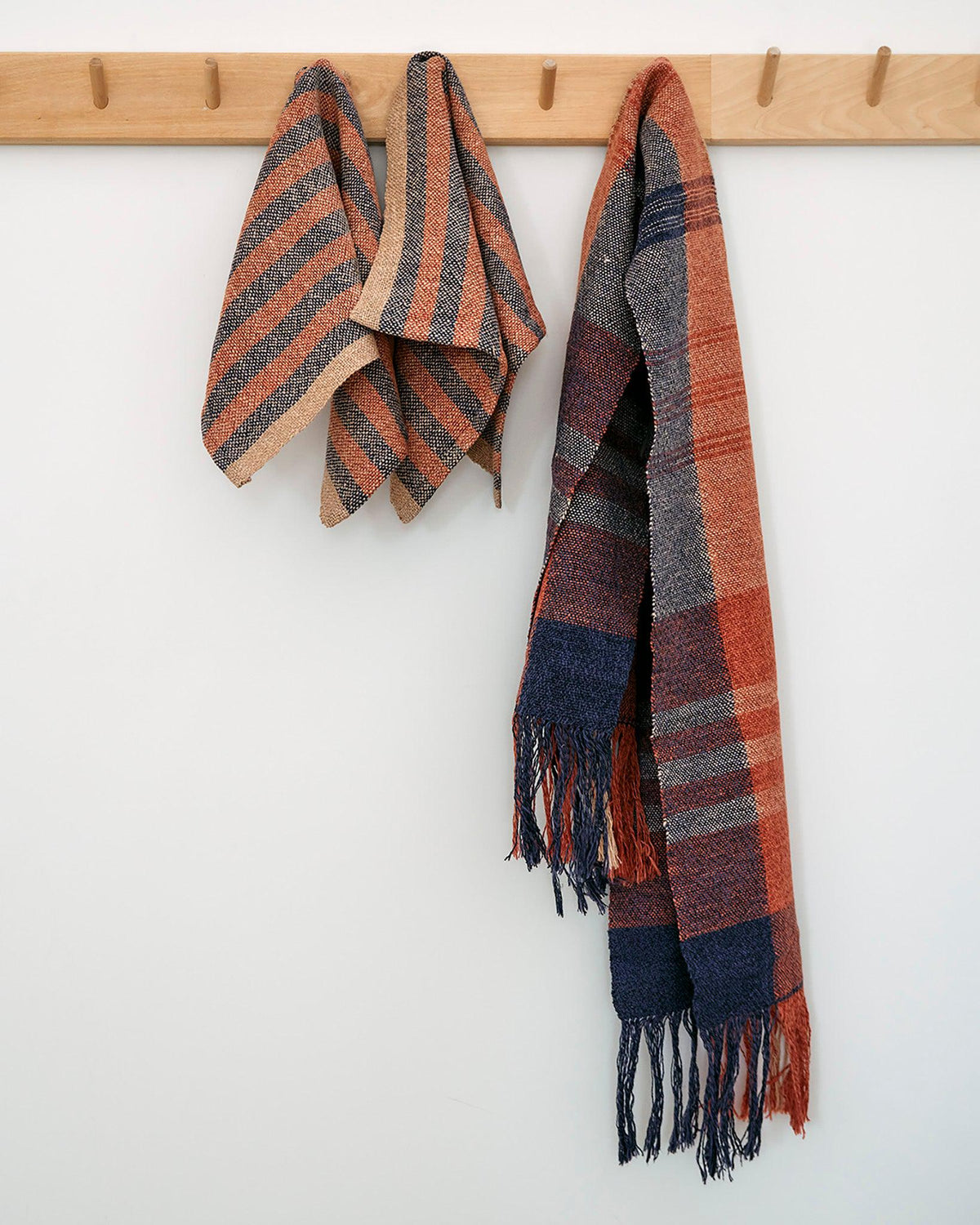 Duet Favorites - Set of Two Patterns with striped Citrus Towels and plaid Minimalist Scarf in warm colors hanging on wooden hooks